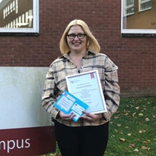 amanda standing outside the college holding a certificate