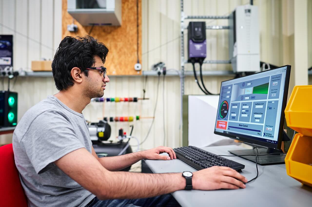 Student working on a desktop computer connected to a wind tunnel
