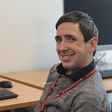 simon sitting in the IT hub beside a computer