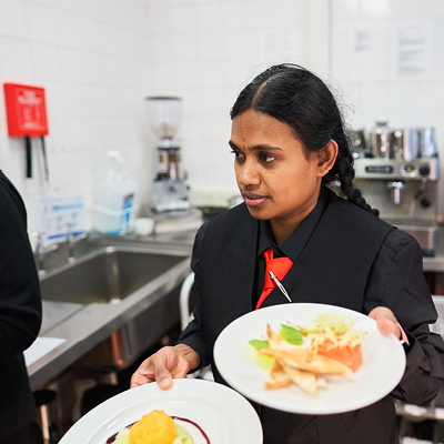 student carrying plates from the kitchens