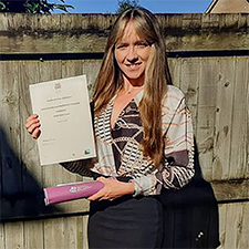 susan holding her graduation certificate in garden