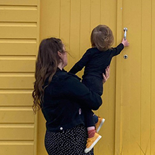 lucy with her child facing a beach hut