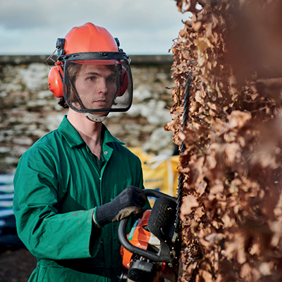 student using hedge trimmer