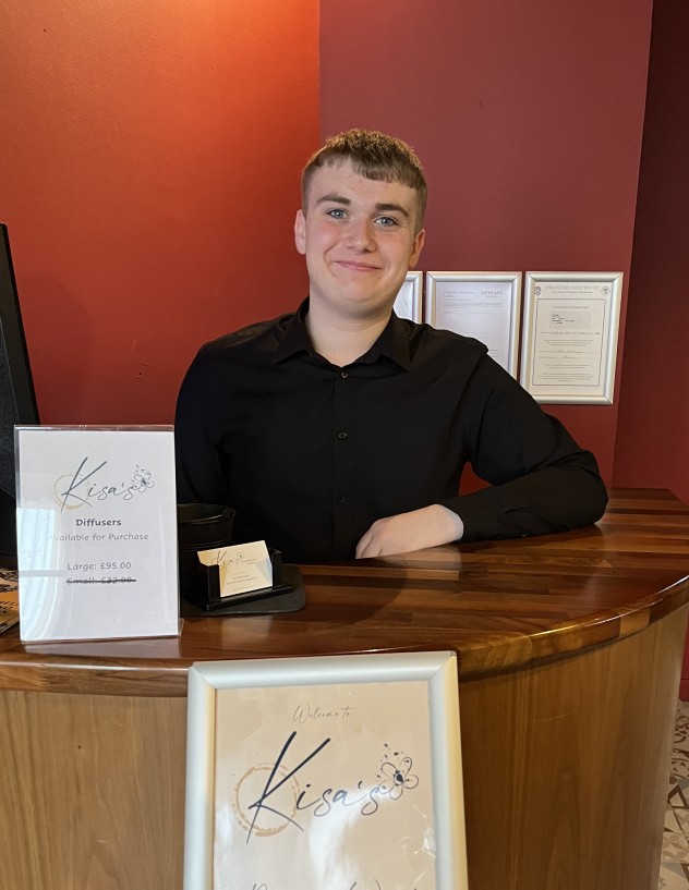Former student standing behind work counter at restaurant Former student standing behind work counter at restaurant