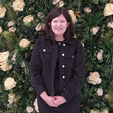 rachel standing with a flower background wall