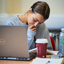 student working on a laptop with a costa coffee beside them