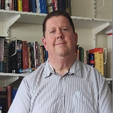 ronnie in his office with books behind him