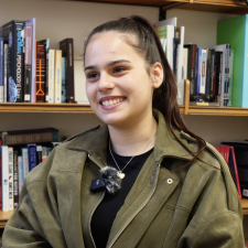 Deni in a classroom with books behind her