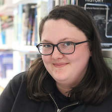 sam standing in the library with books behind her