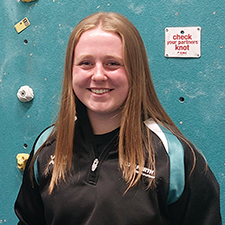 niamh standing in front of the climbing wall in the asw